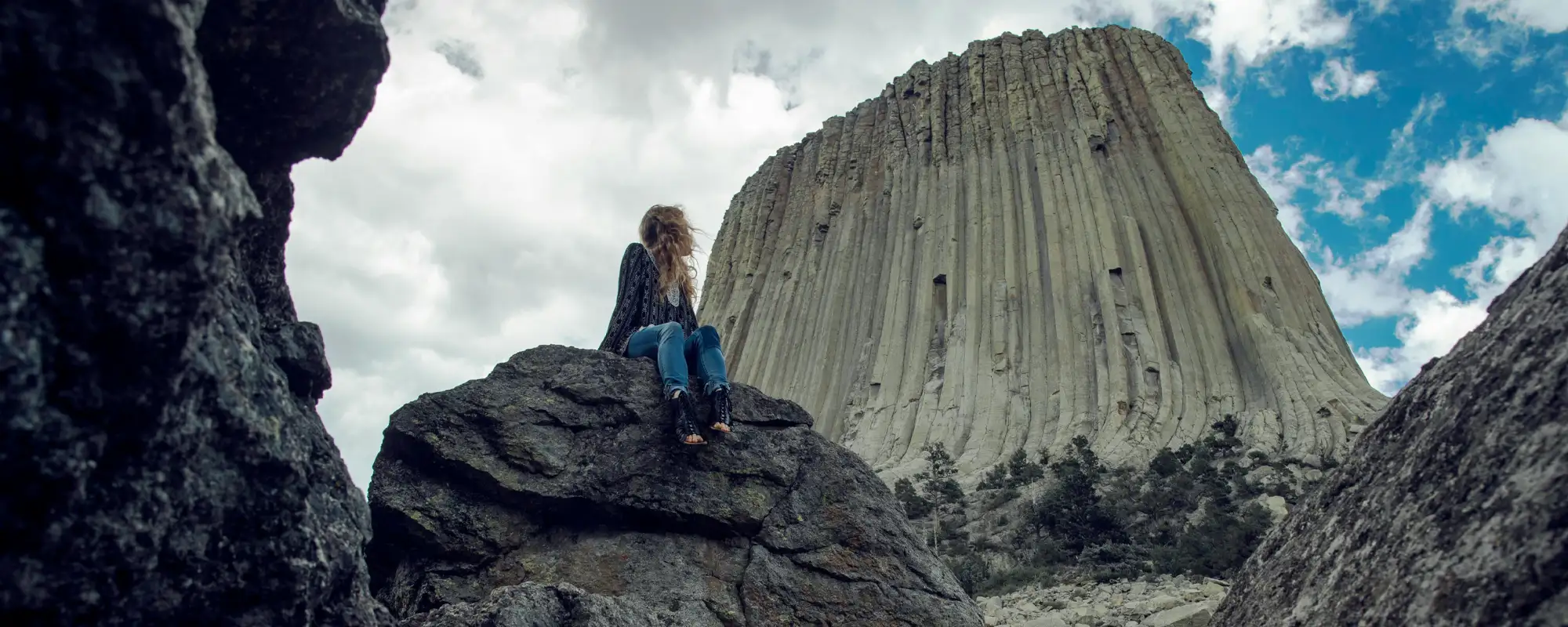 woman sitting on rocks with Devils Tower in the background